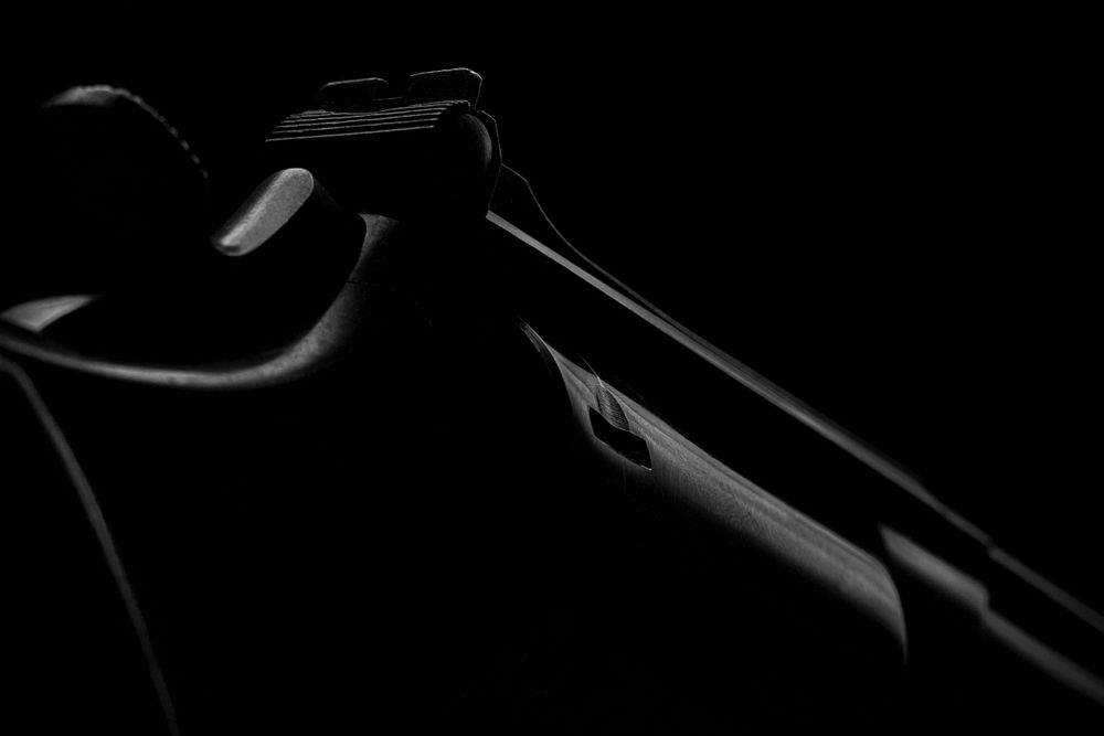 A detail shot of the side of a revolver shot against a black background and low-key lighting.
