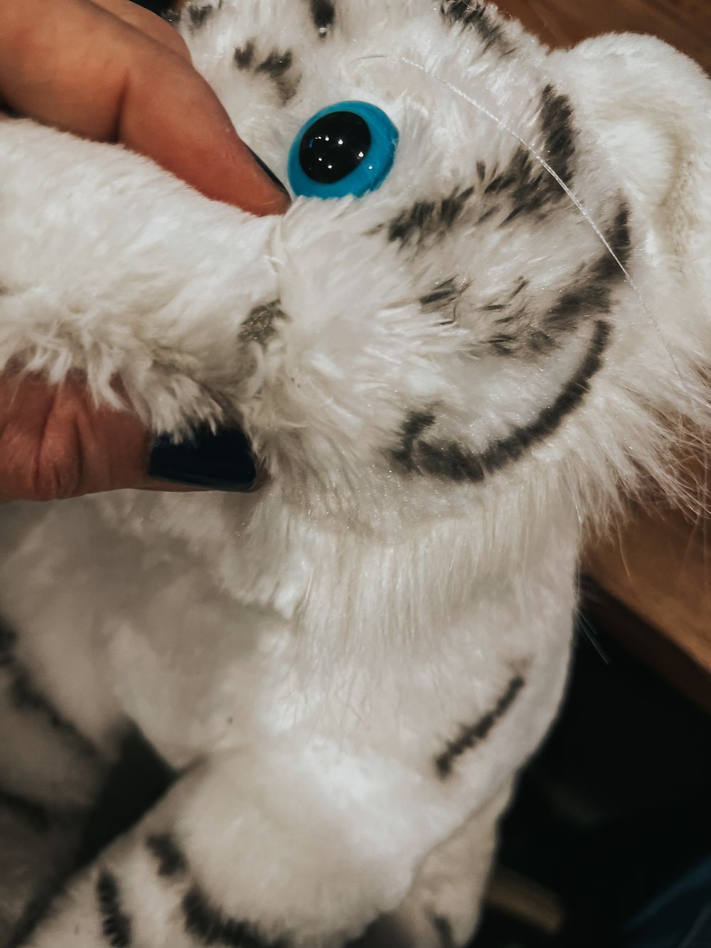 Close up of stuffed tiger eye in mid repair. The eye is a blue safety doll eye.