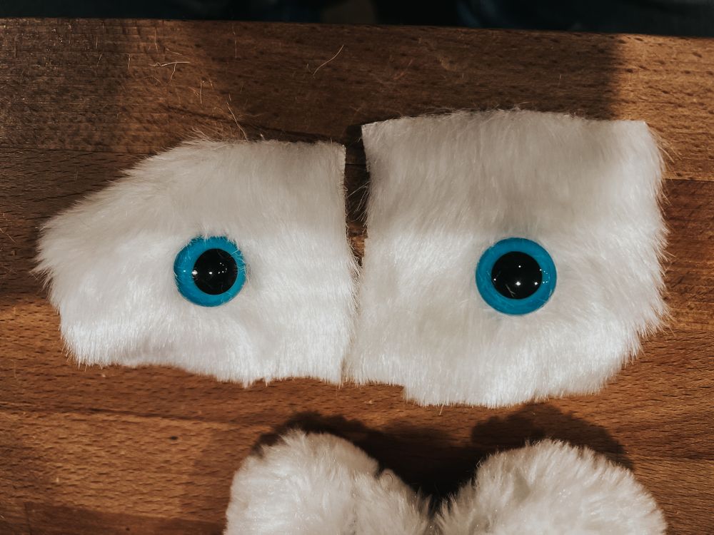 Two blue doll eyes attached to two small pieces of white faux fur.