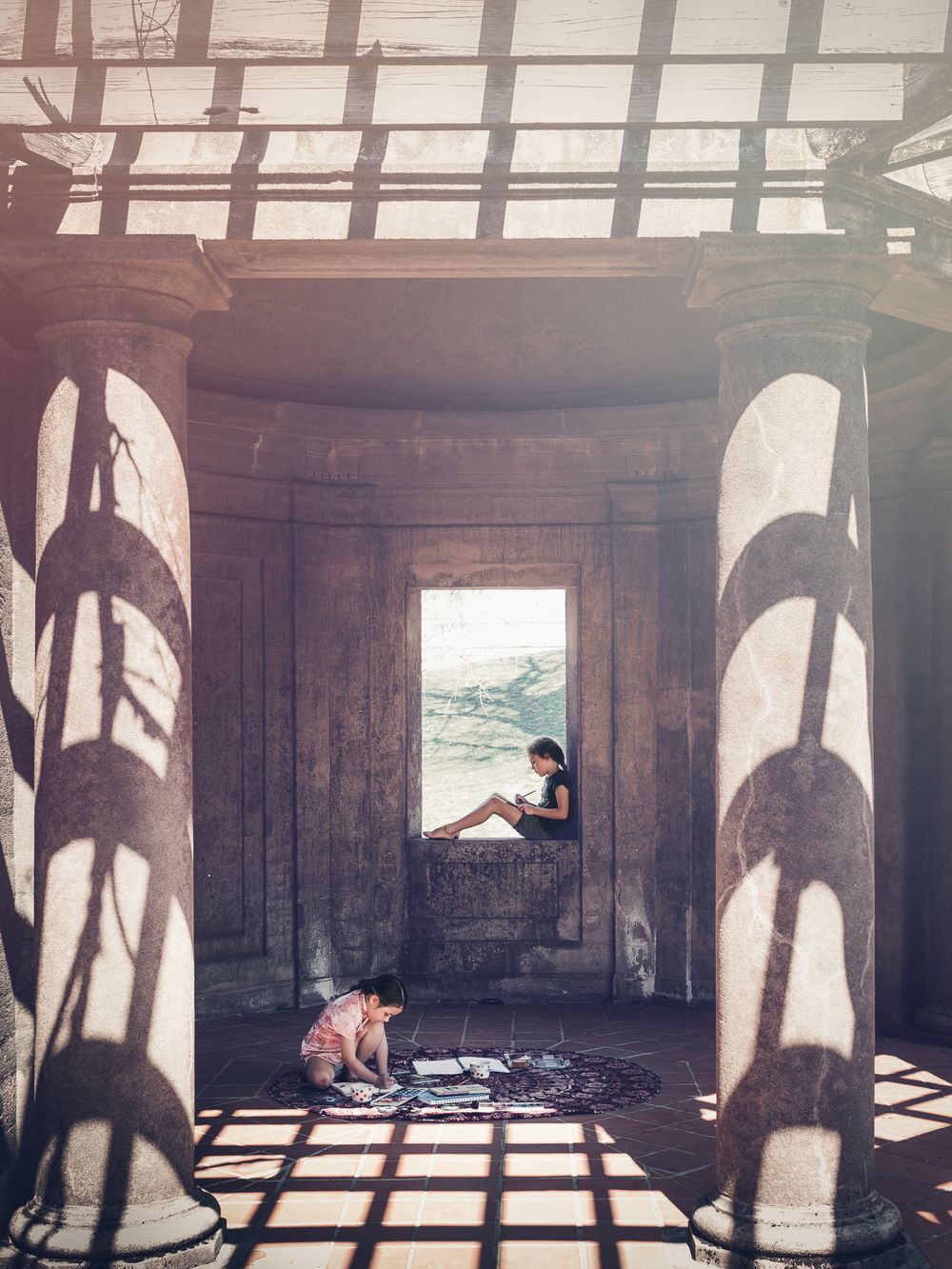 Architectural photo with dramatic shadows cast through columns and window openings.