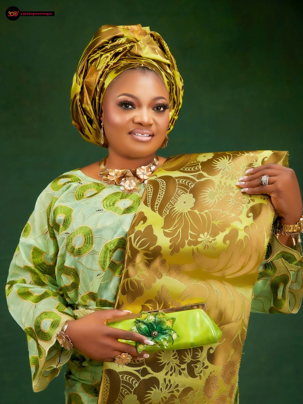 Woman in green gold brocade Nigerian traditional outfit with gele headwrap holds green bow clutch purse.
