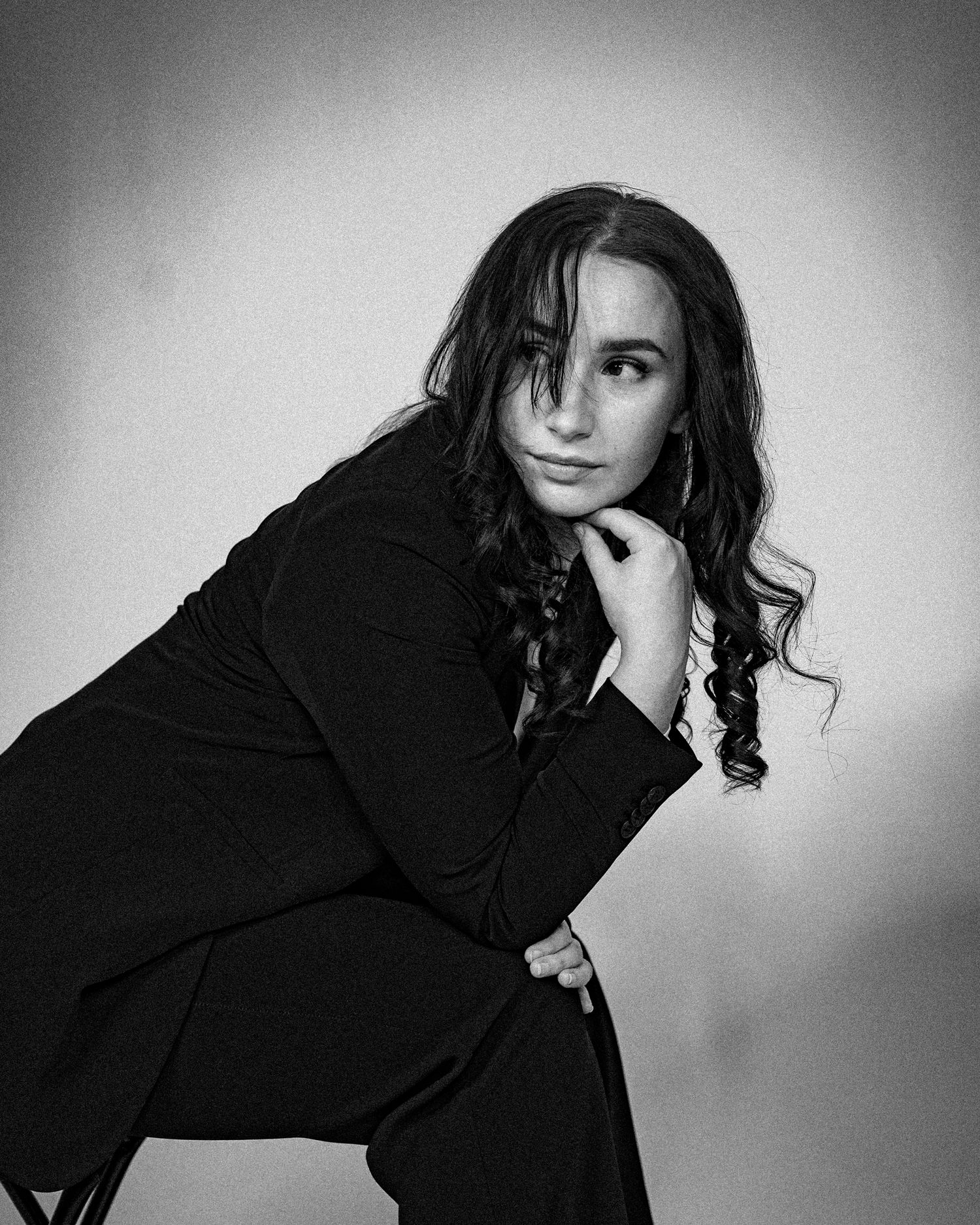 Artistic black and white portrait showing elegant pose in dark blazer.