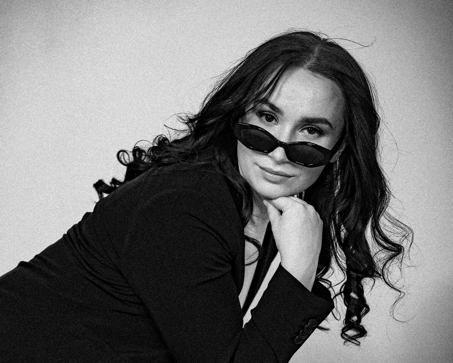 Black and white fashion portrait with sunglasses and dramatic pose.