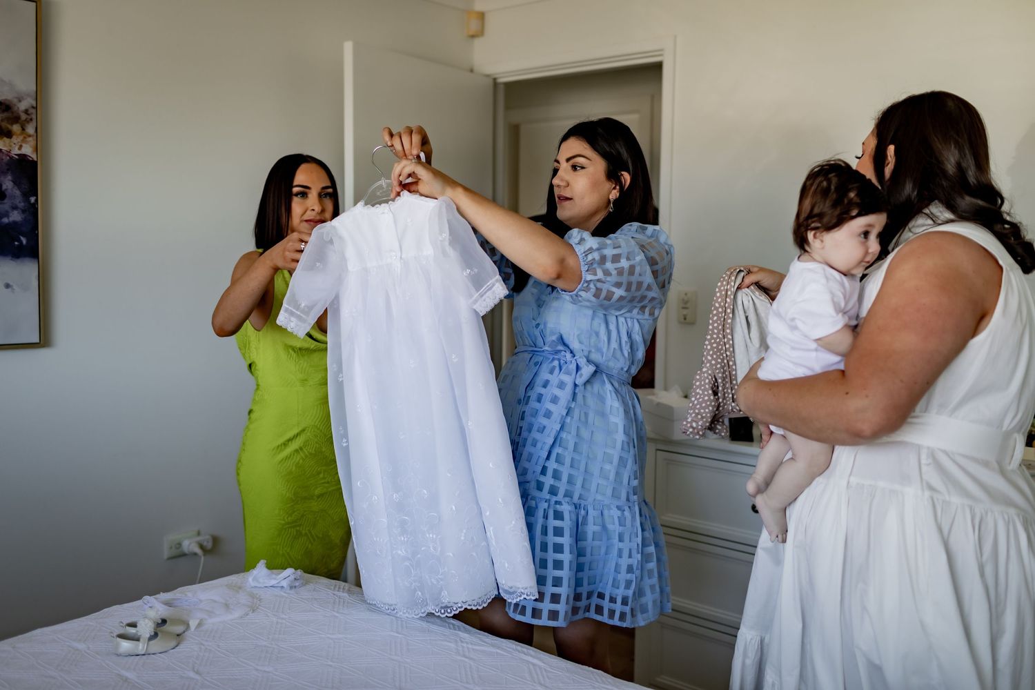 A group admires a traditional white christening gown during a special celebration.
