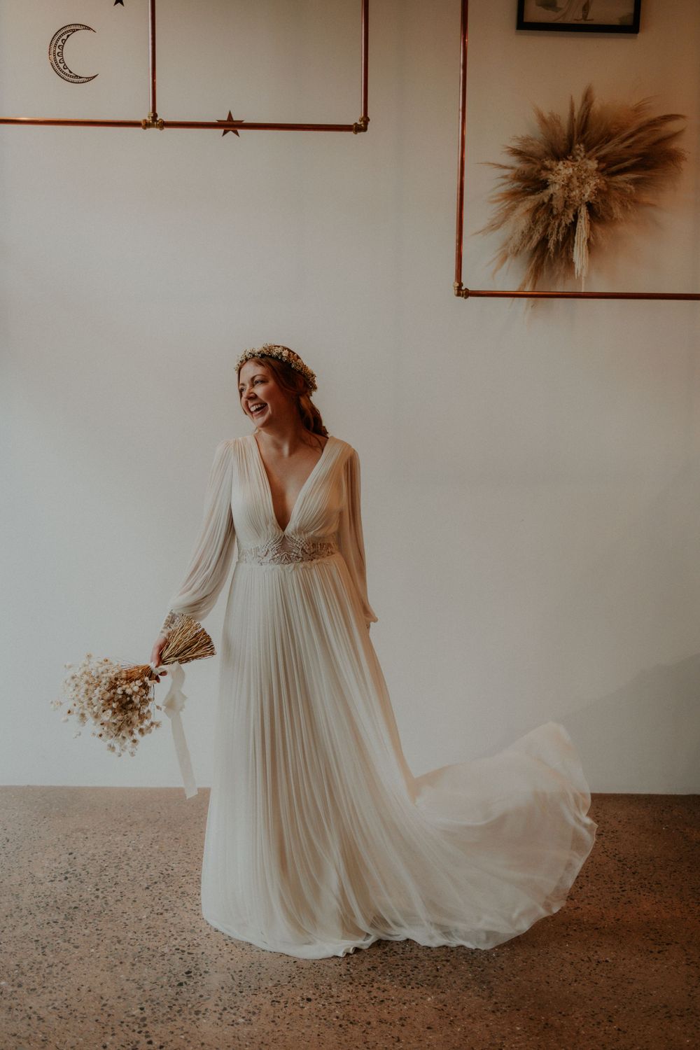 Flowing white wedding dress with bishop sleeves captured in motion against minimal wall decor.