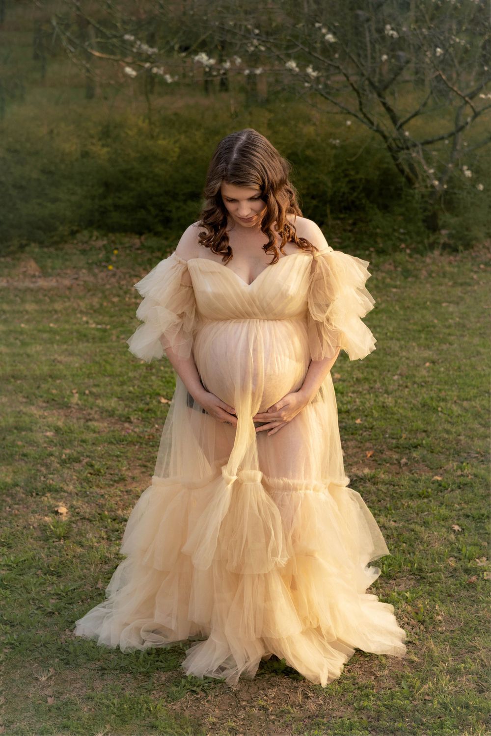 A maternity photo of a woman in a beautiful open front yellow maternity gown.