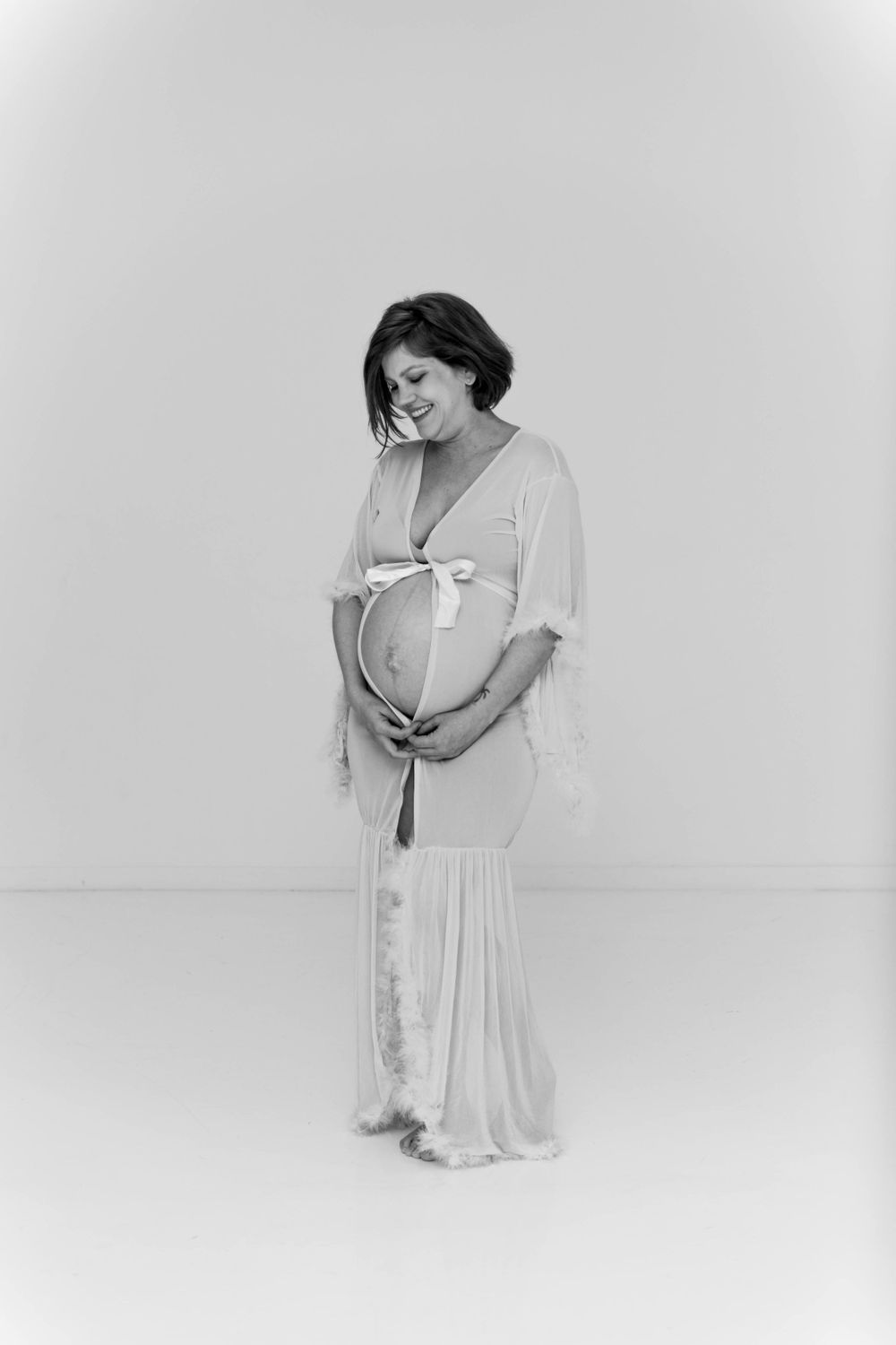 Black and white image of a pregnant woman posing in a robe.