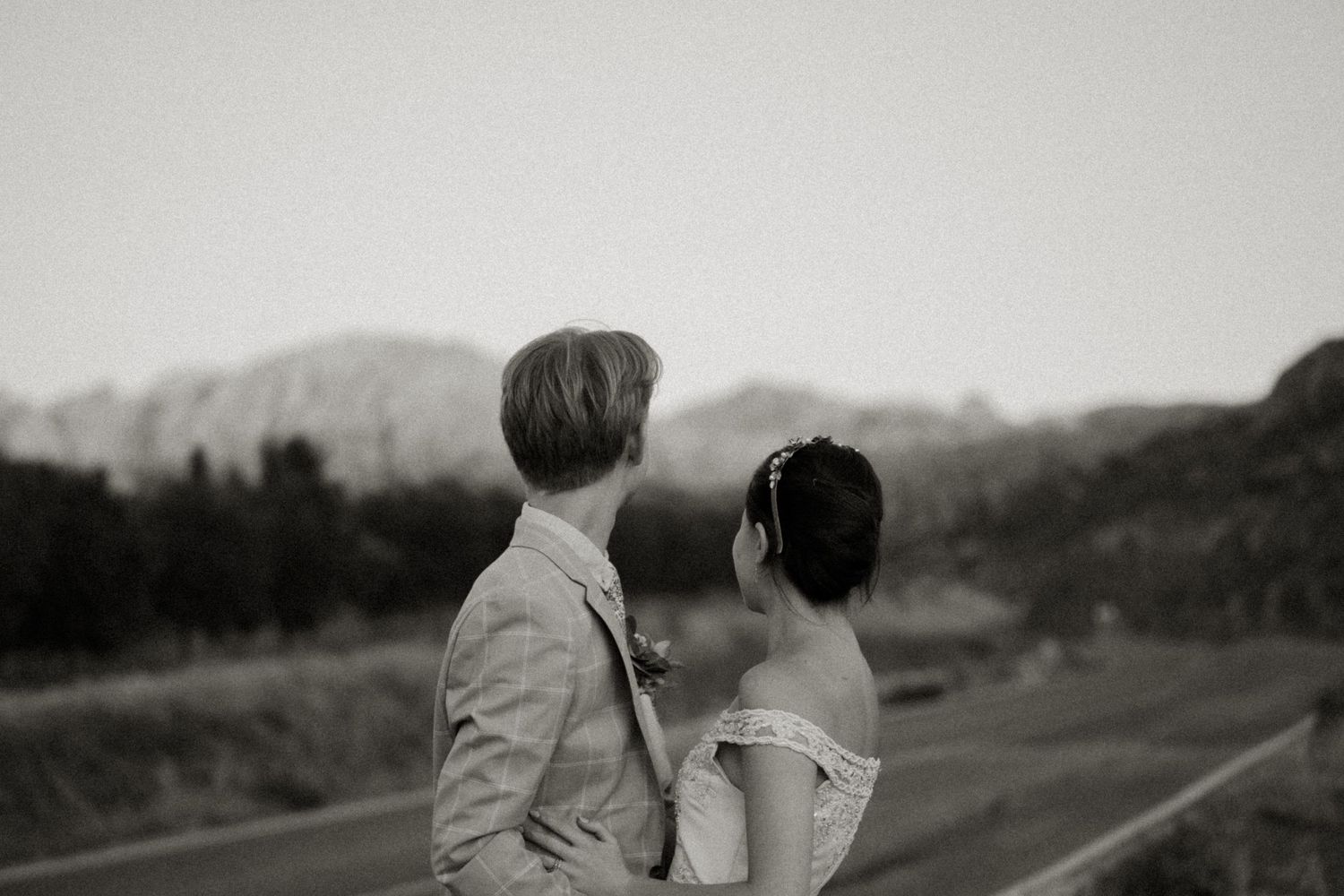 A black and white portrait of newlyweds against a mountainous landscape. Destination Wedding in Malaga, Spain.