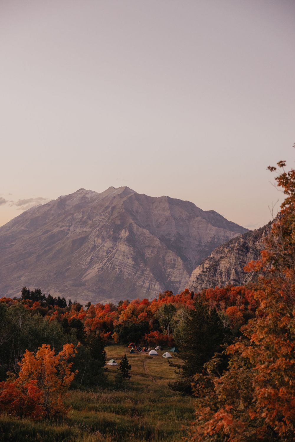 Majestic mountain peak with vibrant orange fall foliage in the foreground during autumn.