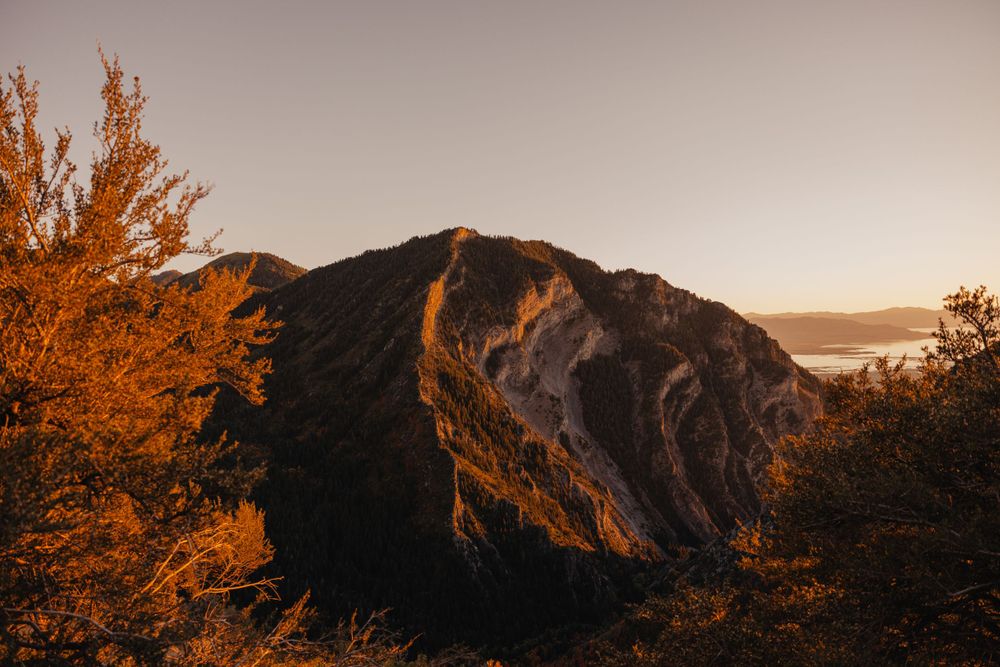 Rugged mountain landscape bathed in warm sunset light with golden autumn vegetation.