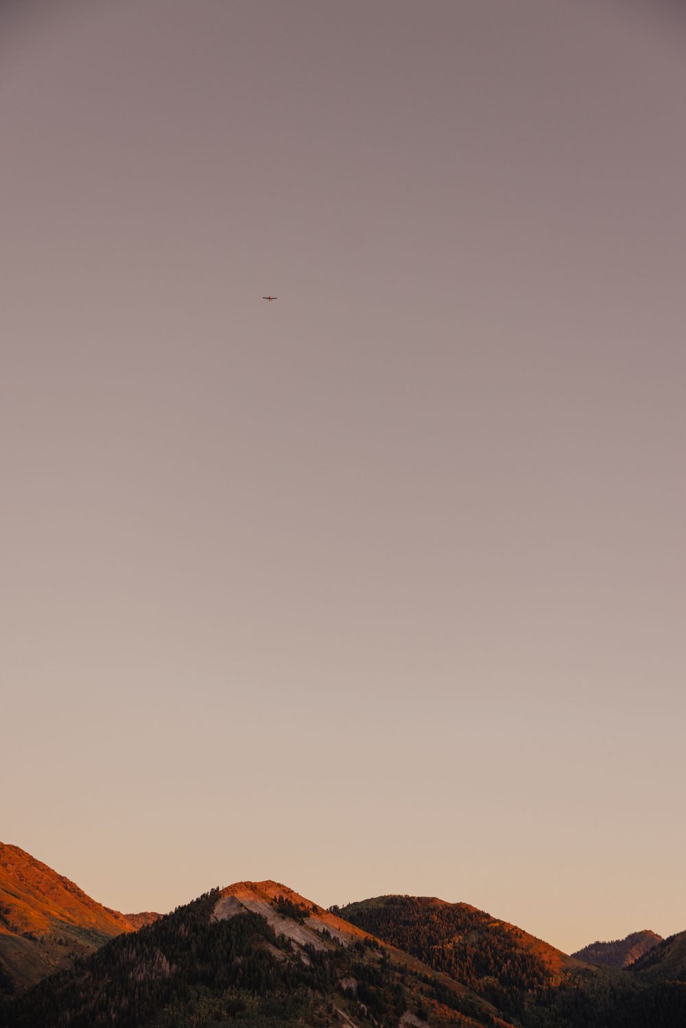 Mountain peaks silhouetted against a pastel twilight sky with golden hour lighting.