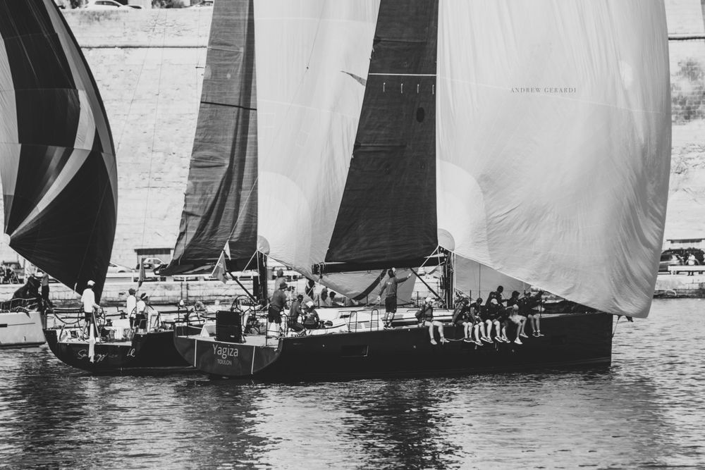 Vintage black and white photograph of classic sailboats racing in formation.