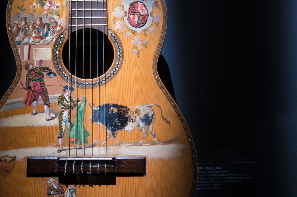 Detailed view of a vintage acoustic guitar with decorative artwork on its wooden body.