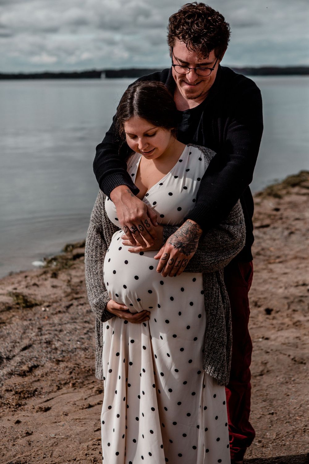 Intimate beachside maternity photos with couple in polka dot dress and cardigan.