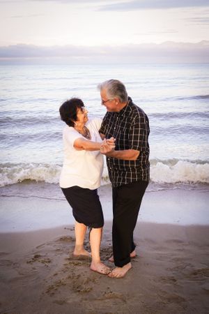 A loving couple dances barefoot on the beach at sunset.