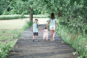 Two people walking together on a wooden pathway surrounded by lush greenery.
