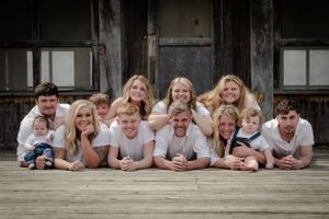 Group lies casually on rustic wooden deck for relaxed outdoor portrait session.