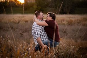 A couple embraces in a tender moment at sunset in a golden field.