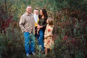Family gathering in natural setting with autumn foliage in background.