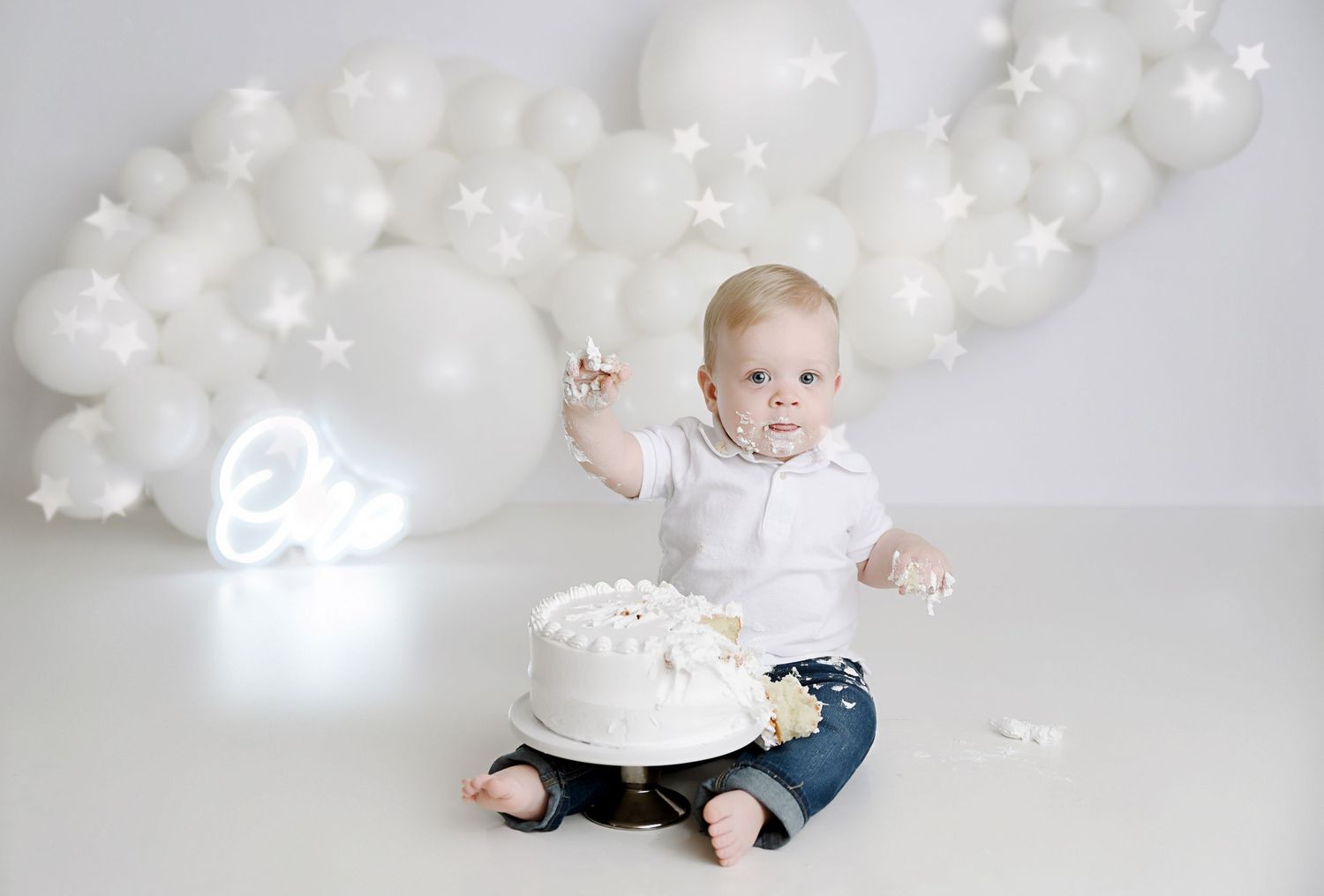 Baby's first birthday cake smash with white balloons and star decorations on a clean white background.