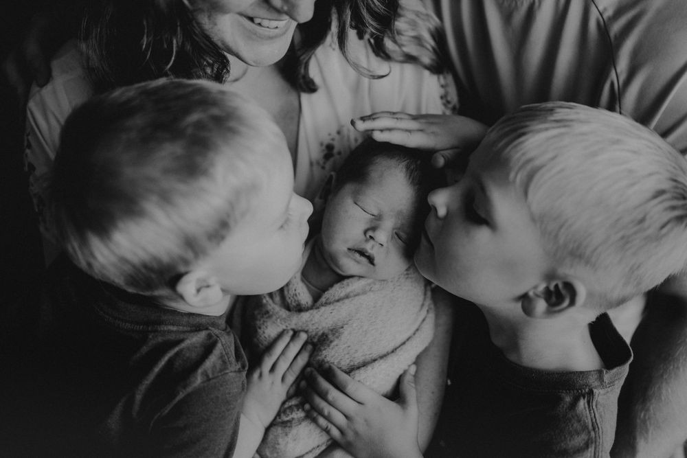 Black and white portrait of family sharing intimate moment with newborn.