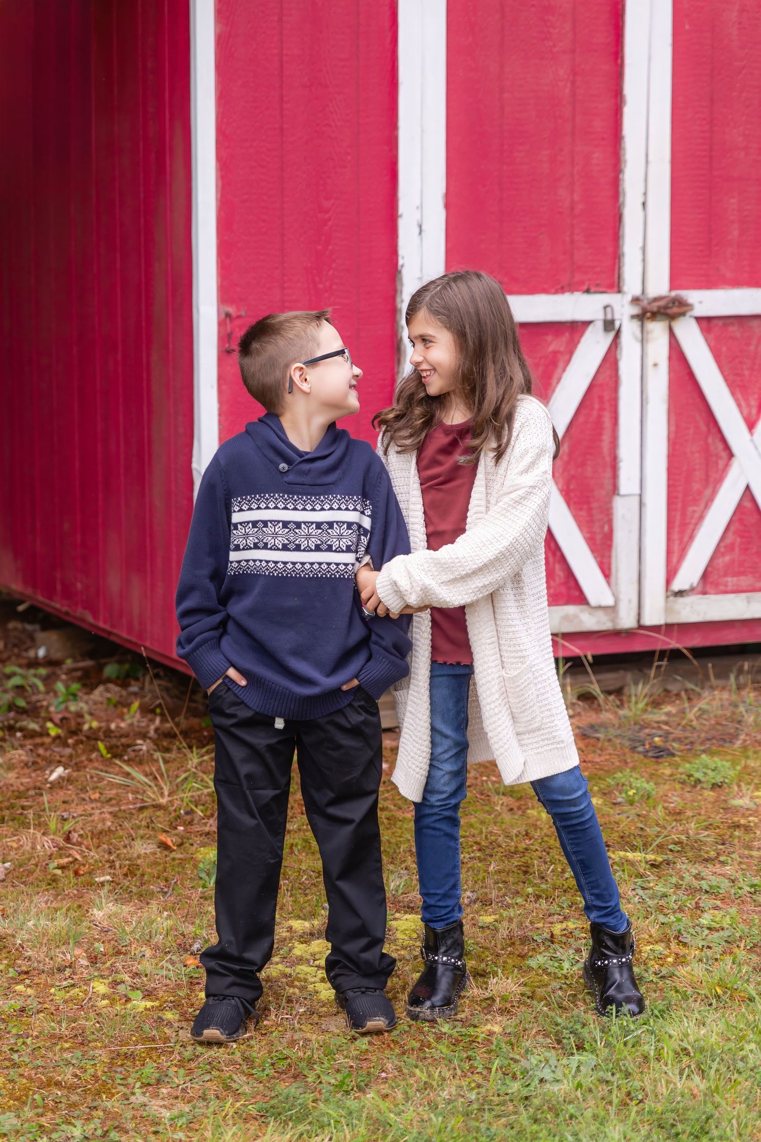two kids hugging while looking at each other in front of red barn at turkey trac farm in millville new jersey cumberland