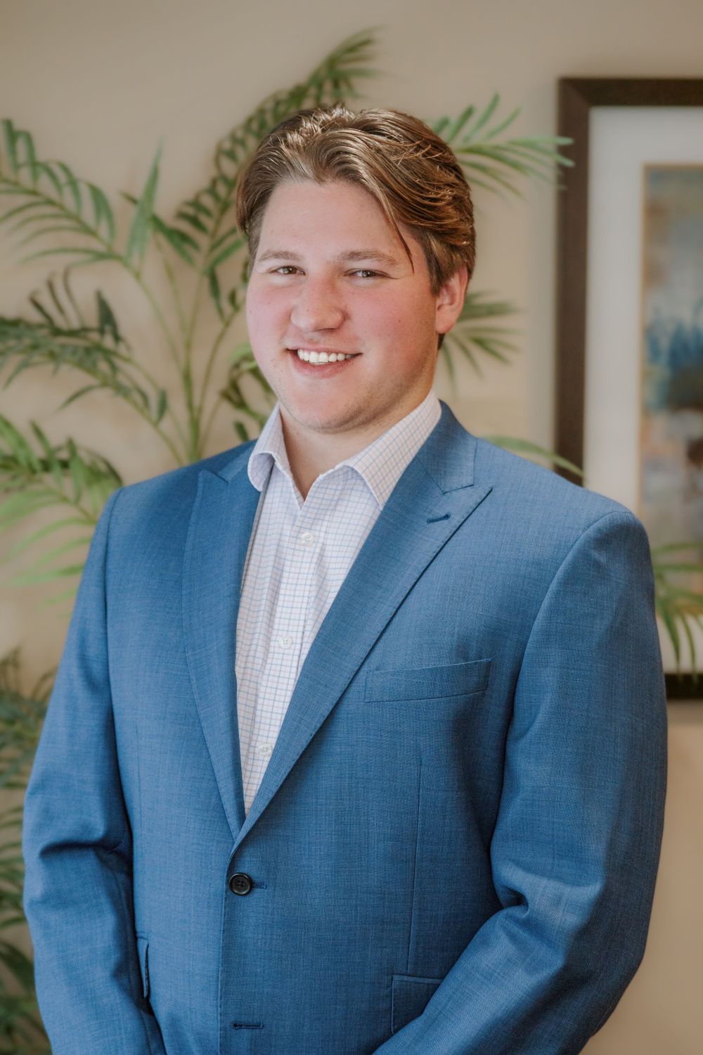 Professional indoor portrait against a tropical plant background.