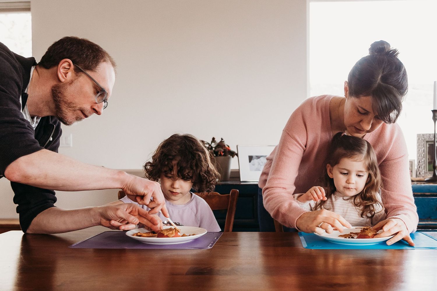 Family sitting at dining table eating a meal together.