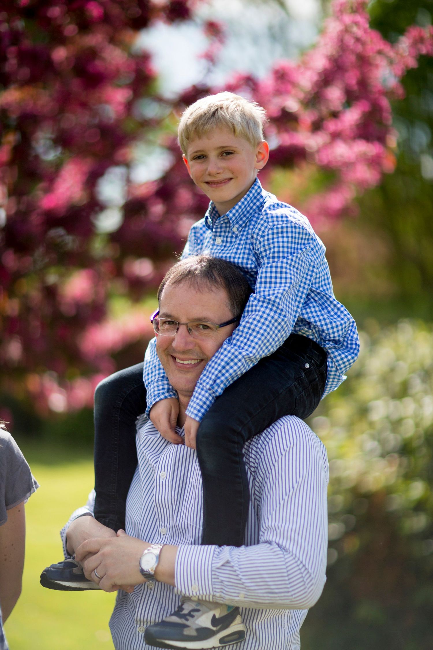 A tender outdoor portrait with spring cherry blossoms blooming in the background.