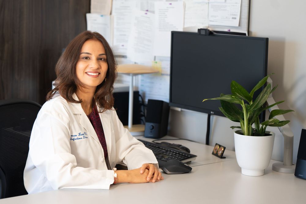 Healthcare professional in white coat sitting at desk with computer monitor and plant in office setting. Quad Cities Business Headshot Photo