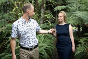 Engaged man leads his girl through lush green ferns