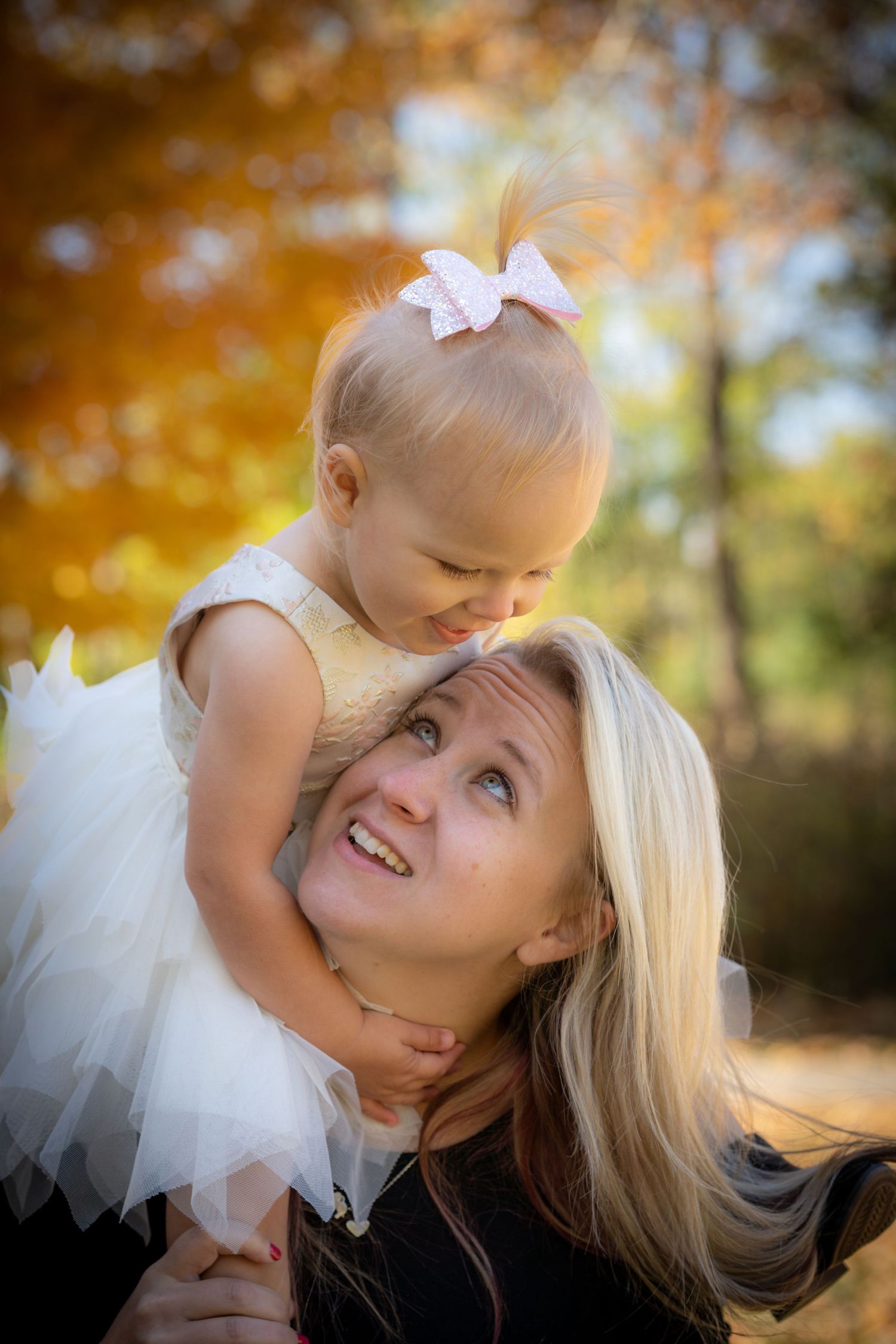 Sweet autumn portrait series showing tender moments between parent and child with golden foliage in background.
