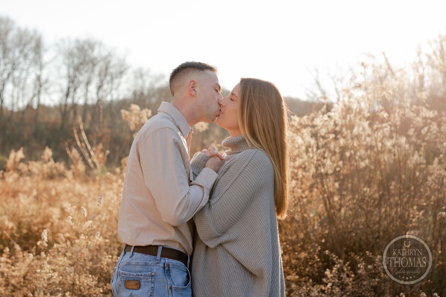 A sweet romantic moment between a couple standing in a golden field during sunset.
