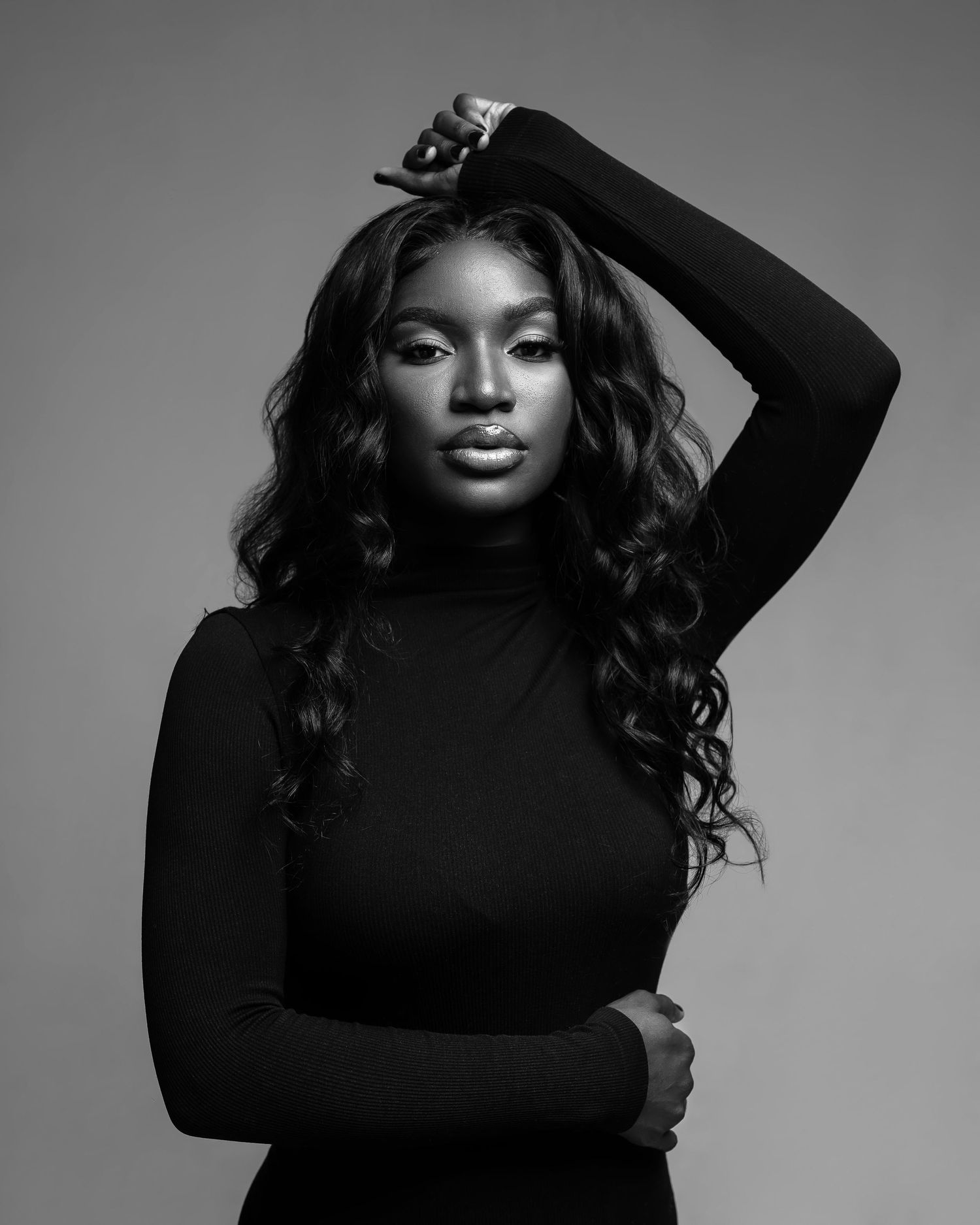 Black and white portrait of a model in a turtleneck sweater with flowing curls.