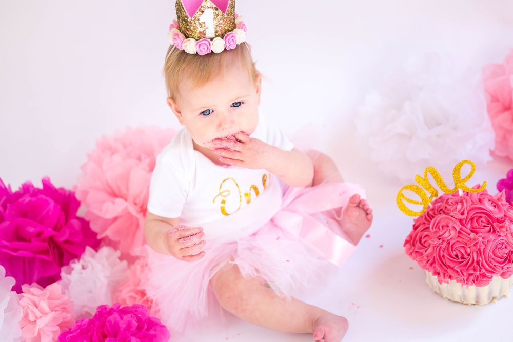 Dreamy pink and white birthday photoshoot with gold lettering and decorative elements.