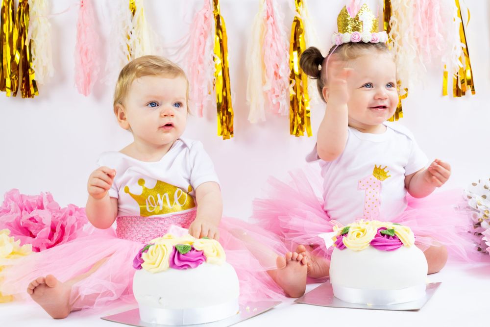 Celebratory cake smash photo setup with pink tulle and hanging gold tassels.