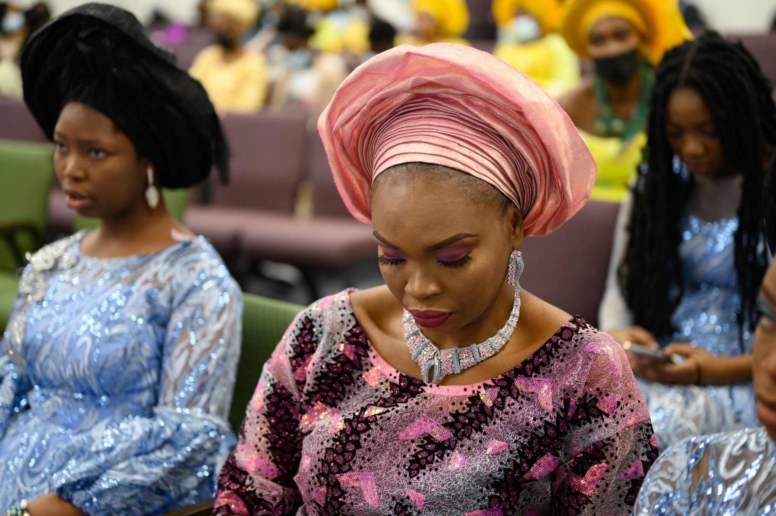 Women in traditional African attire seated at formal celebration event.