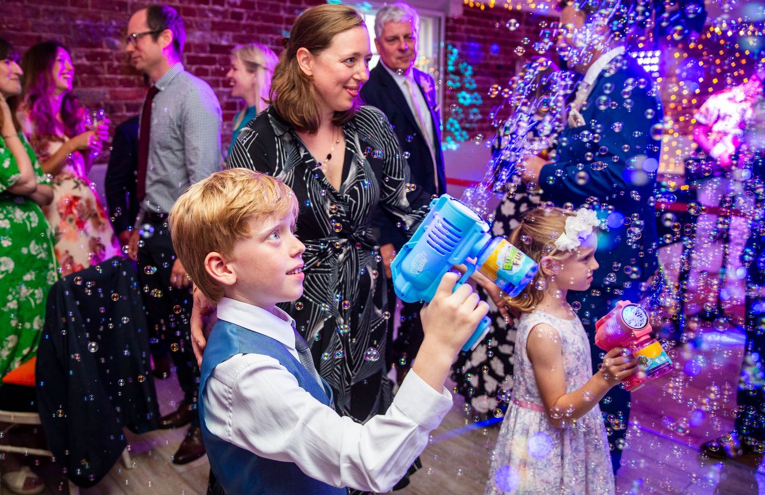 Young guests play with bubble machines during a festive wedding reception.