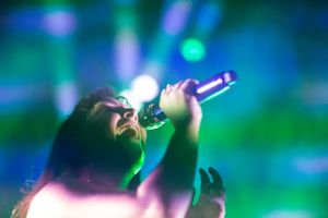 Dynamic stage performance captured with blue and green lighting effects creating an ethereal atmosphere.
