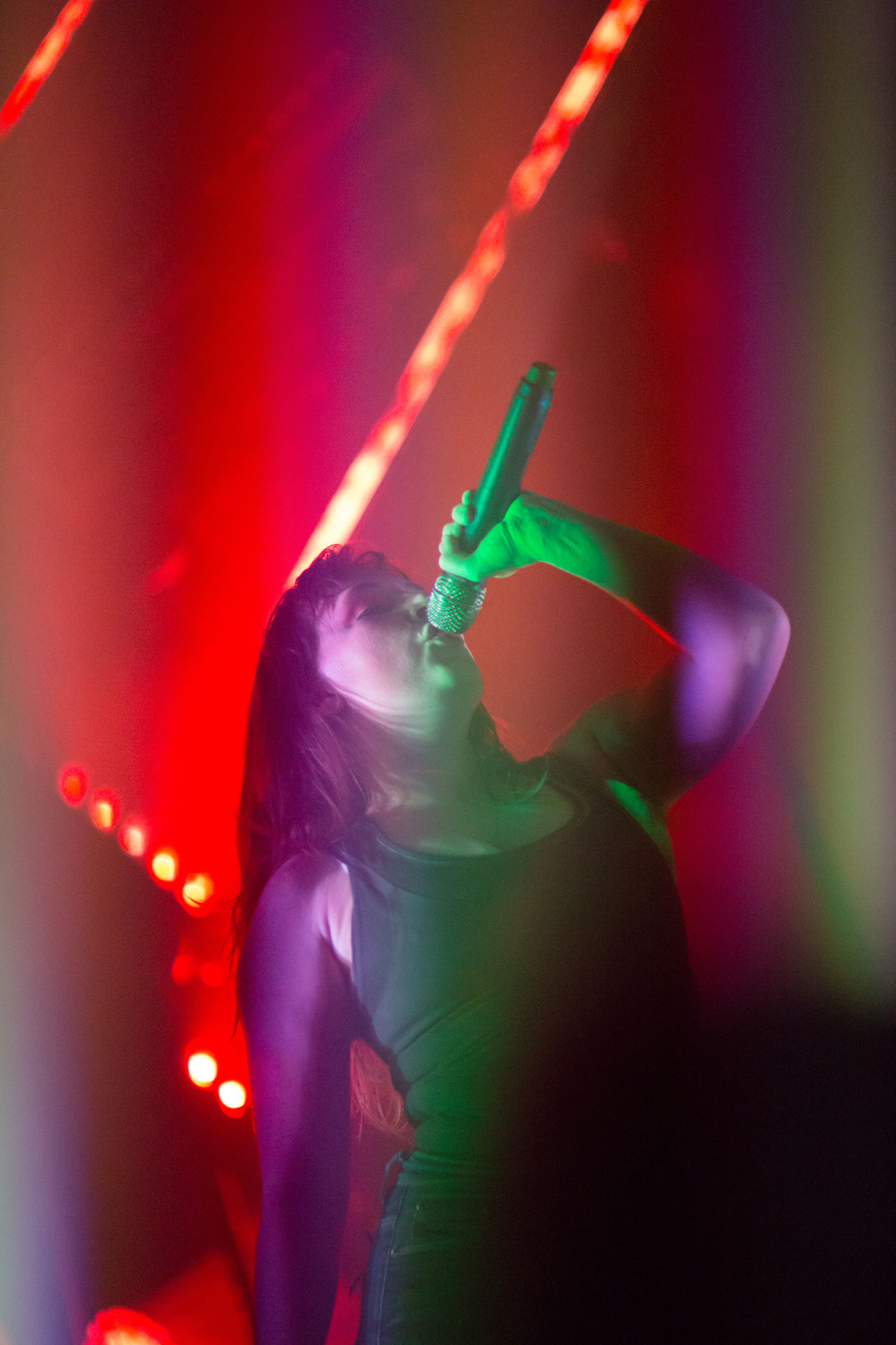 Dancers move under colorful stage lighting with red and purple hues.