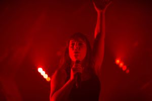 Dramatic red stage lighting creates silhouettes during a performance.