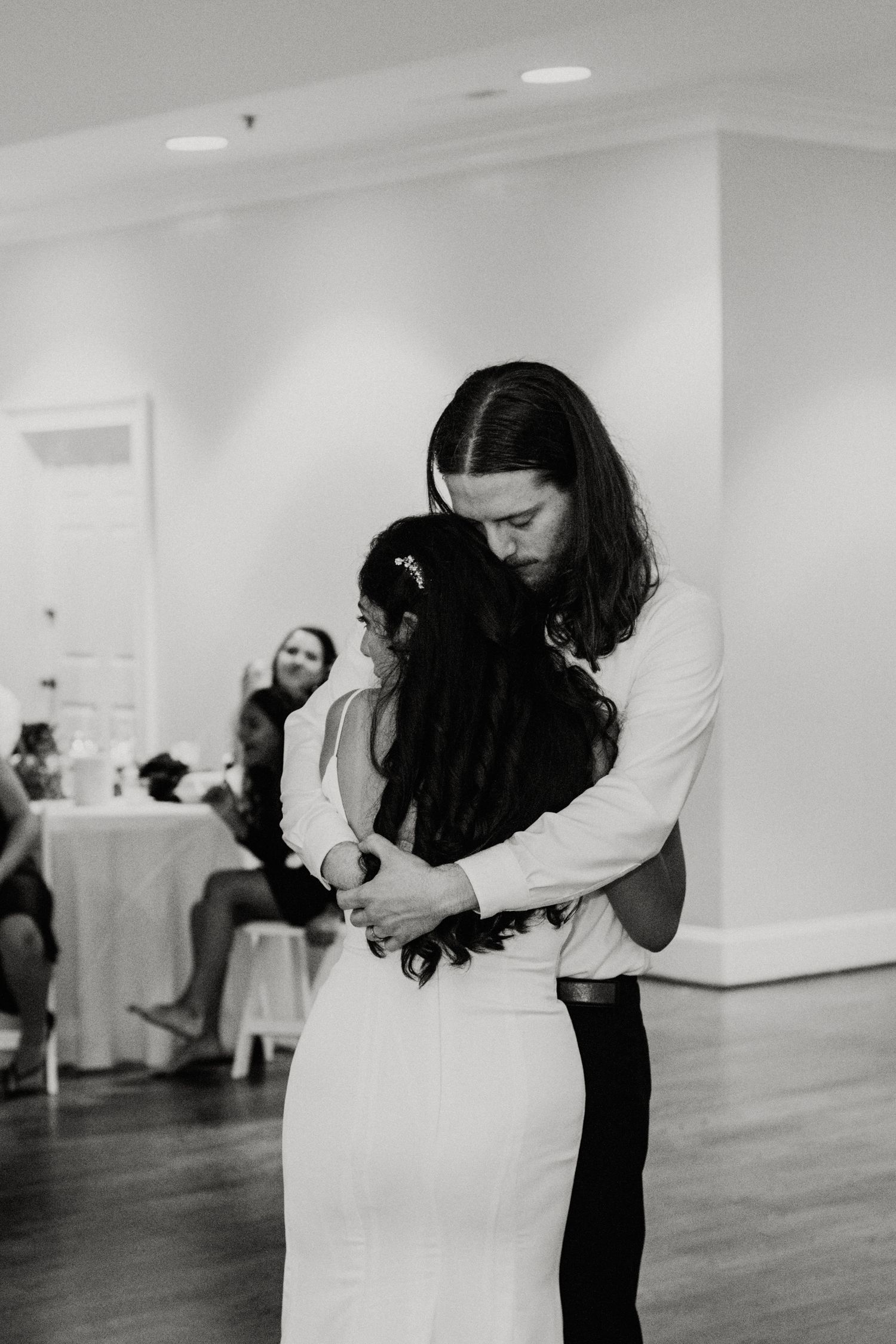Black and white photo of a couple sharing an intimate slow dance at their wedding reception.