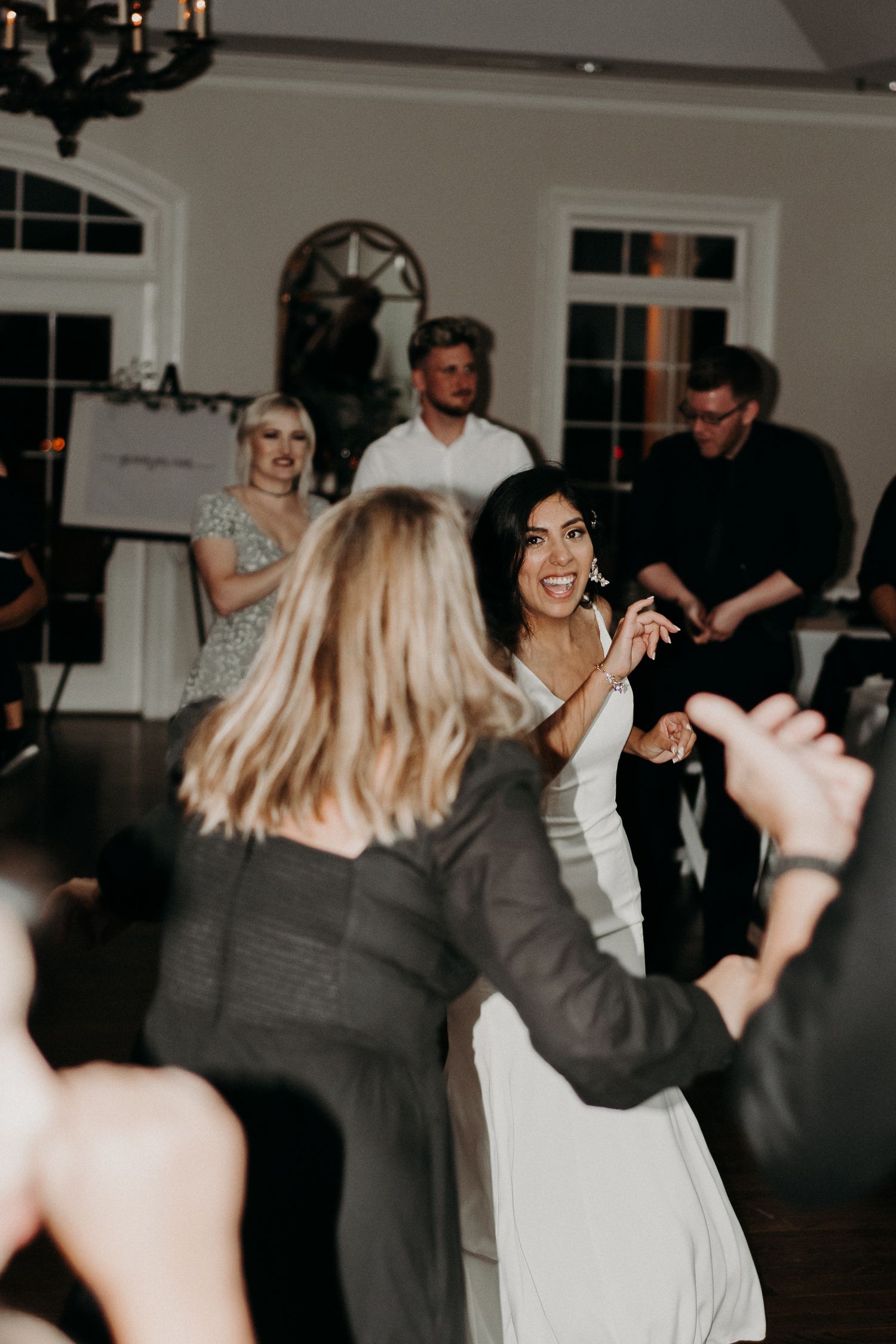 Guests dancing and celebrating at a dimly lit indoor wedding reception.