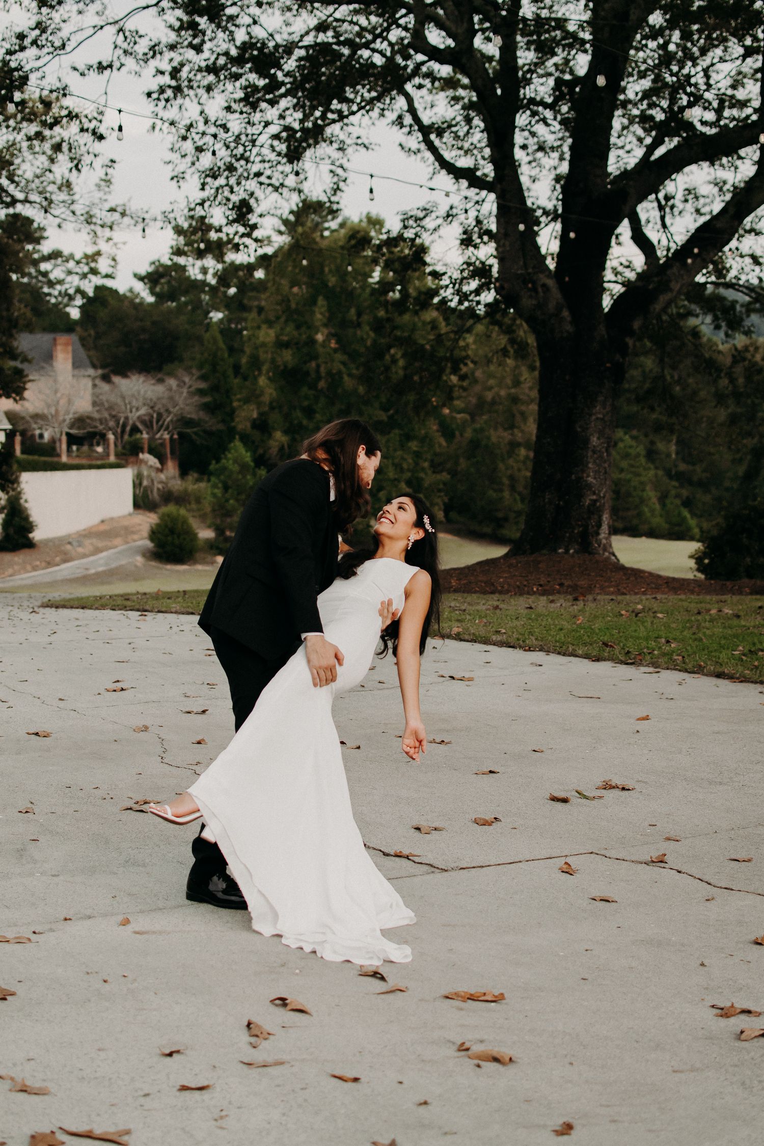 Romantic dip pose on concrete path during wedding photoshoot.