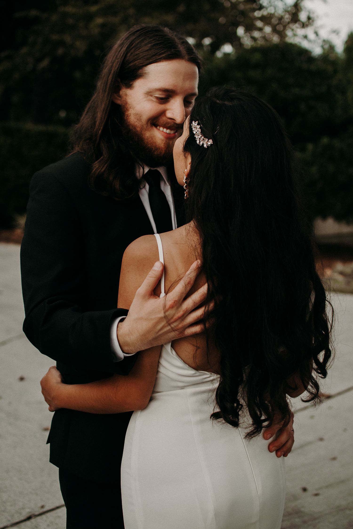A tender moment between newlyweds sharing an intimate embrace outdoors.