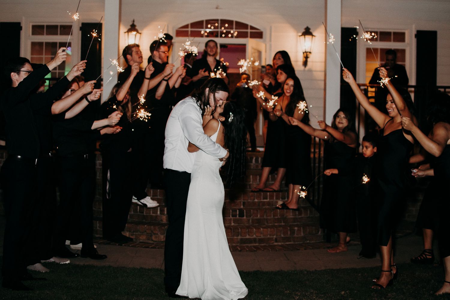 Wedding couple shares a romantic dance while guests hold sparklers forming a tunnel around them.