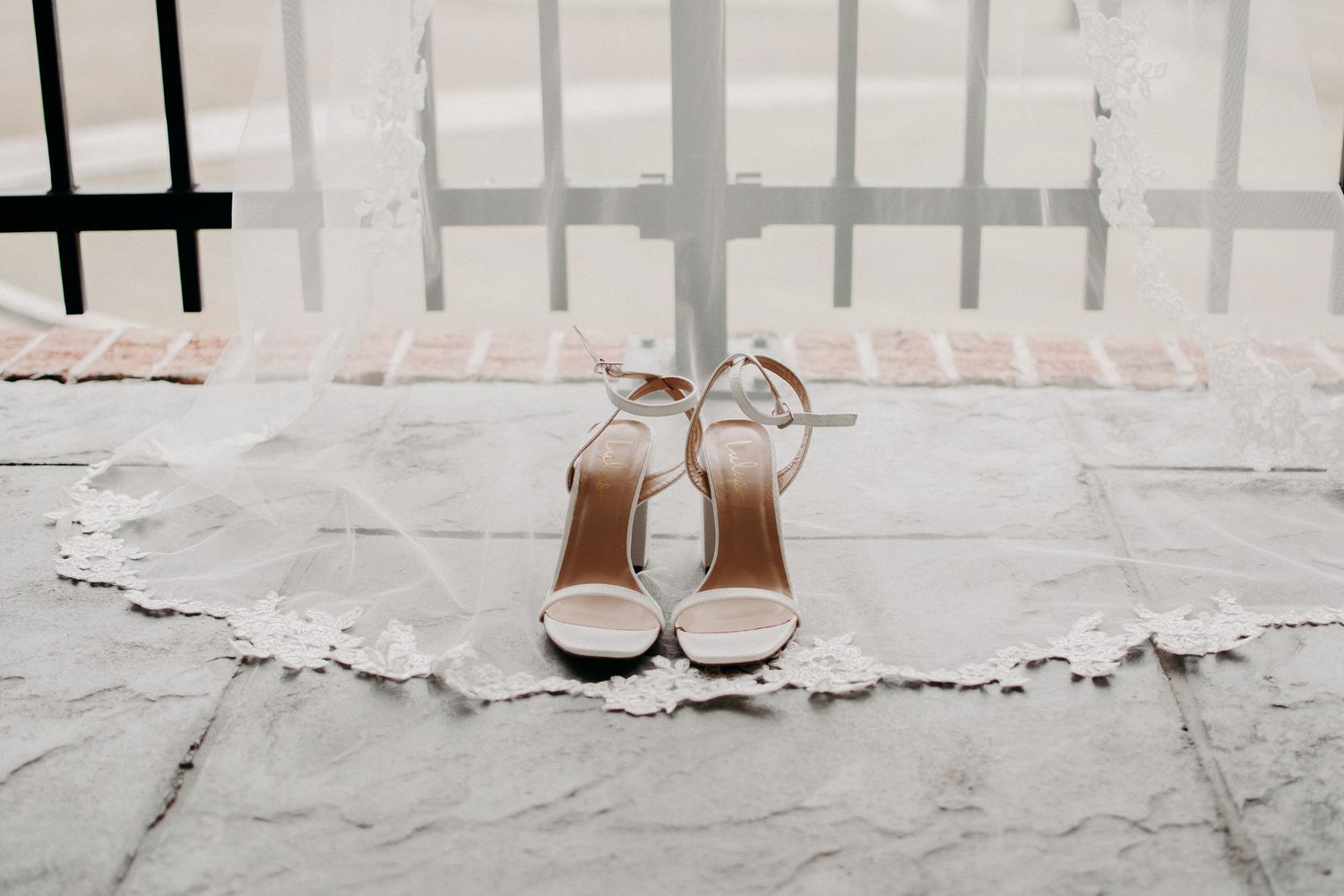 Elegant white bridal heels placed on a textured light surface.