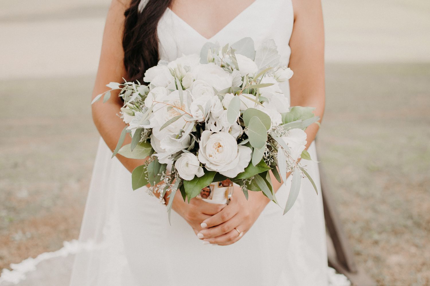 Close-up of white and green bridal bouquet with roses and delicate flowers.
