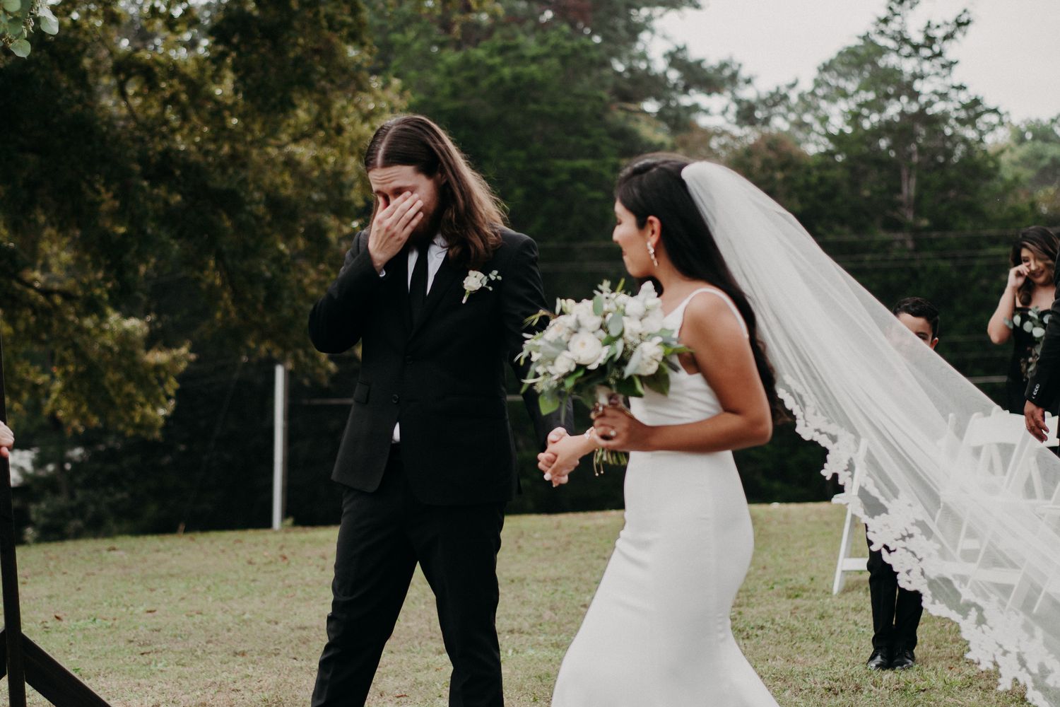A wedding couple shares an emotional first look moment outdoors.