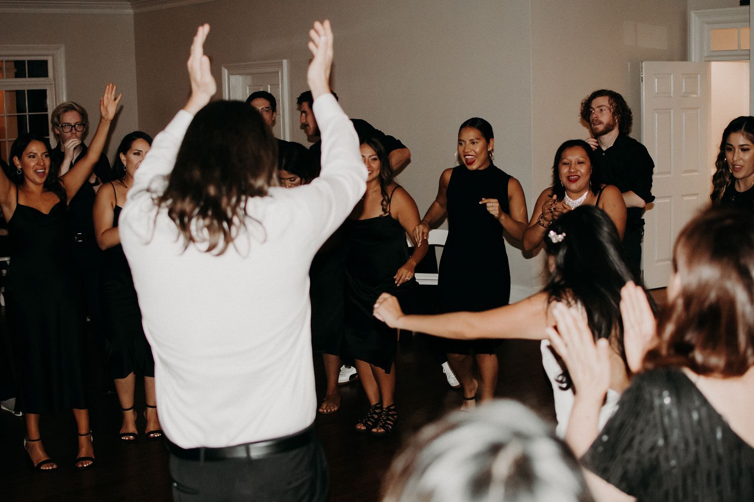 Wedding reception dance party with energetic guests celebrating on dance floor.